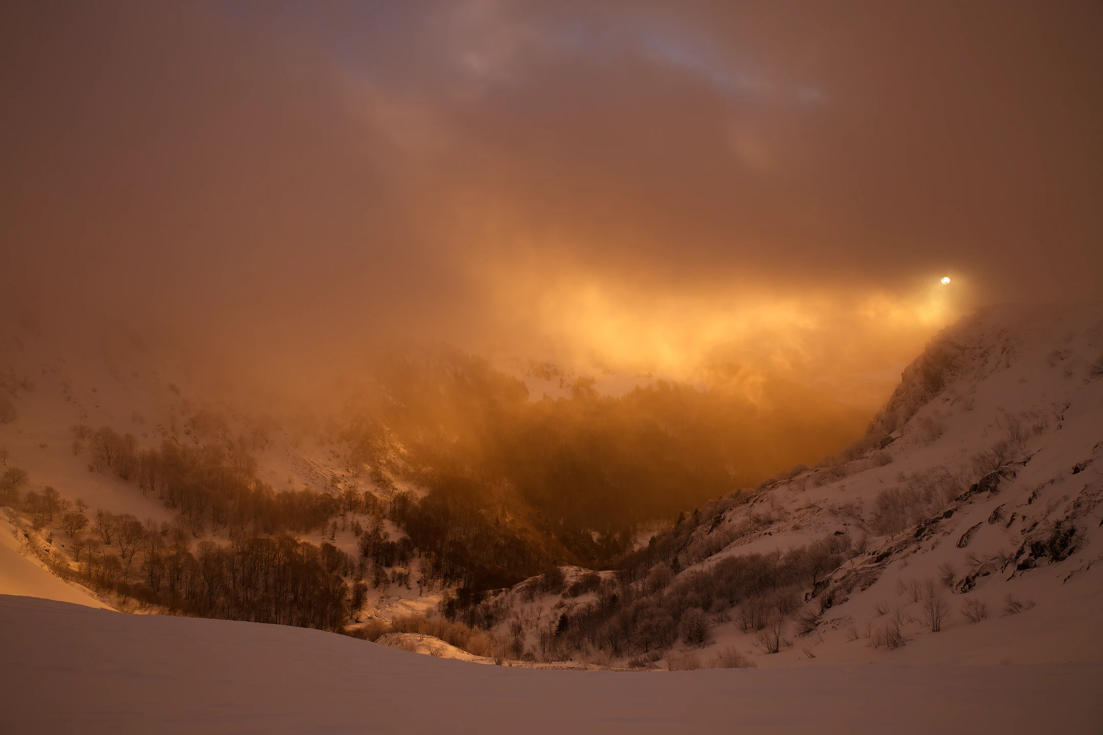 Photo : Cirque du Hohneck enneigé, dans un levé de brume orangée en hiver, Vosges.